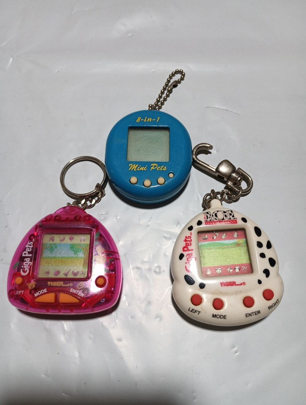two giga pets keychain games and one 8-in- 1 mini pets